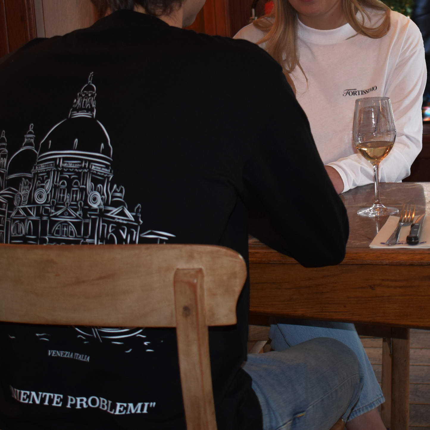 Man and woman in a restaurant setting, showing the Venezia Longsleeve in black and white