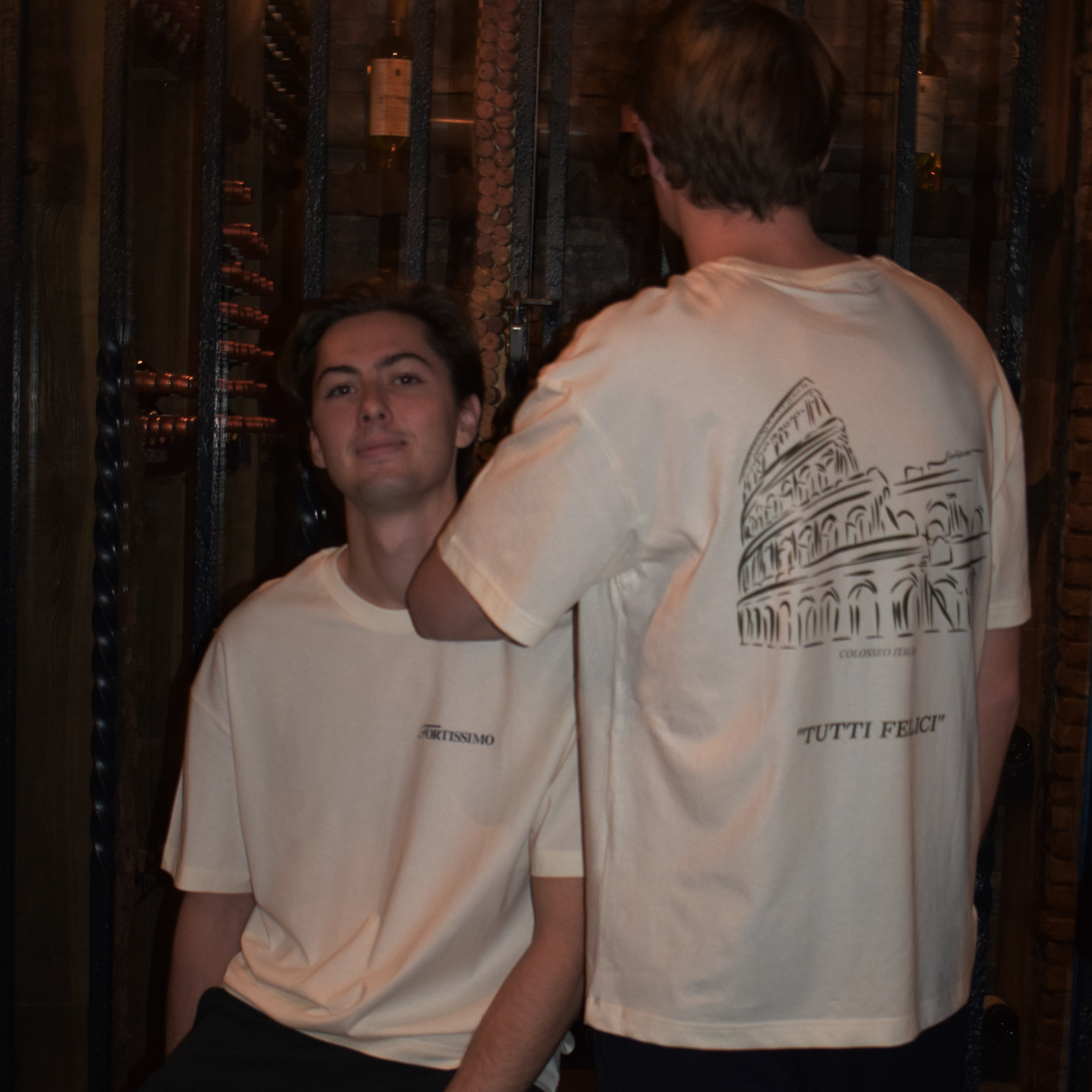 Two men wearing the Fortissimo Colosseo t-shirt in creme where the Colosseo is showing on the back. 