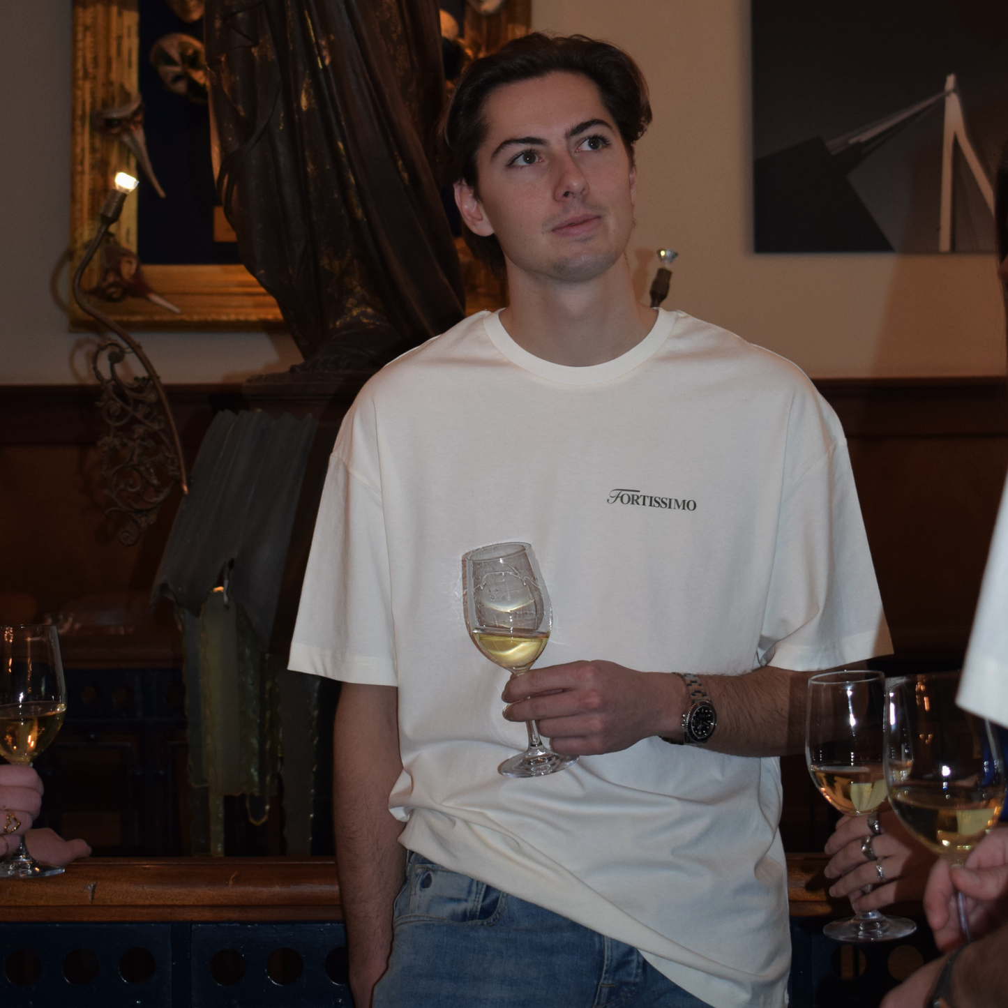 Man in a restaurant setting wearing the Fortissimo Colosseo t-shirt in Creme 