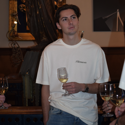 Man in a restaurant setting wearing the Fortissimo Colosseo t-shirt in Creme 