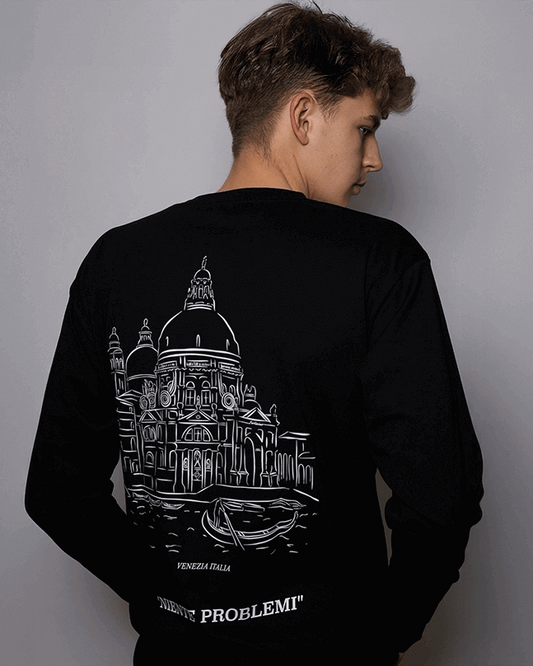 Person wearing a black sweatshirt with a white architectural design on the back against a gray background