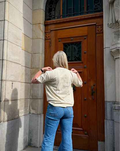 Person standing in front of a large wooden door with decorative ironwork above, on a stone building.