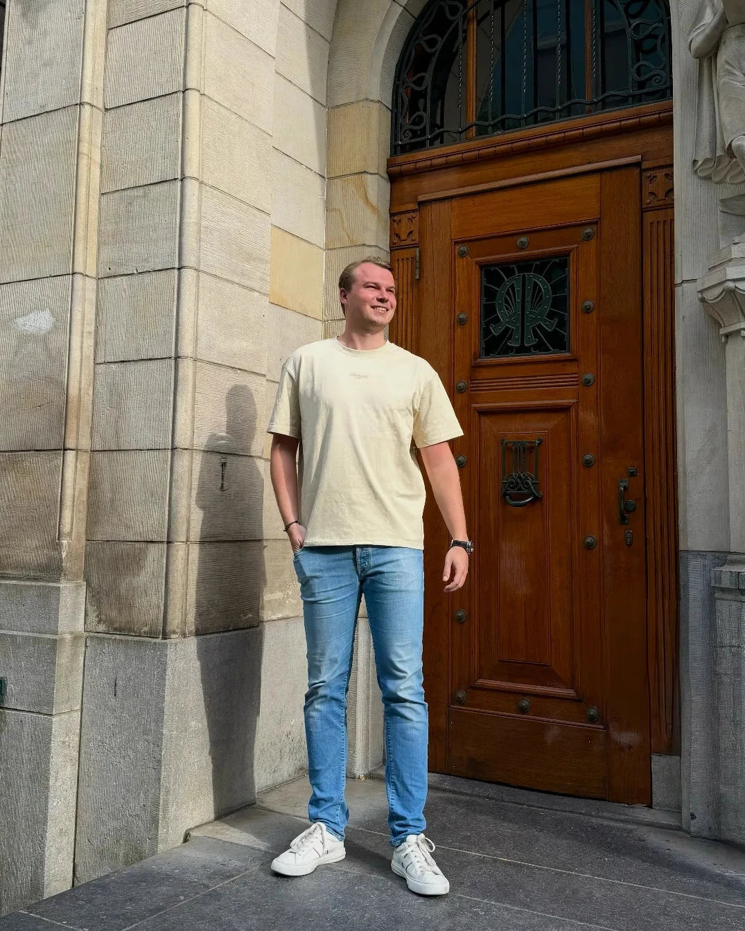 Man standing in front of a large stone building with a wooden door