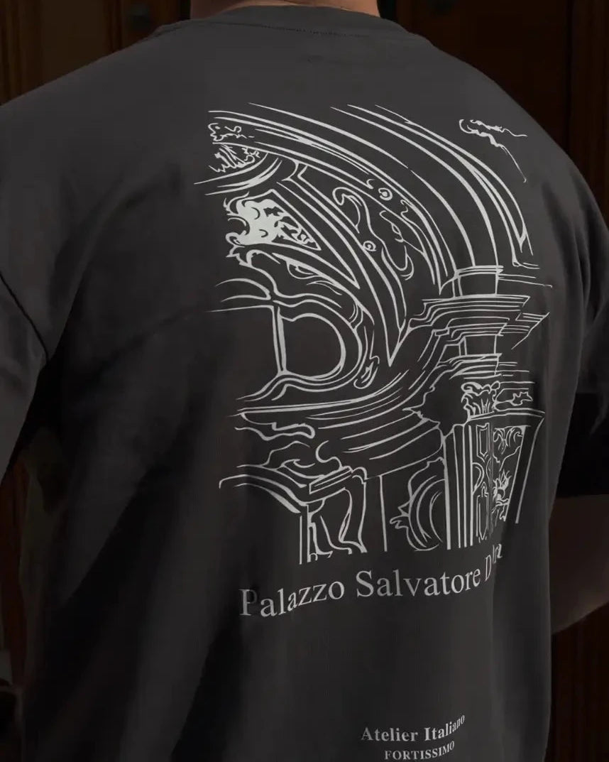 Person wearing a black t-shirt with white architectural design and text on the back.