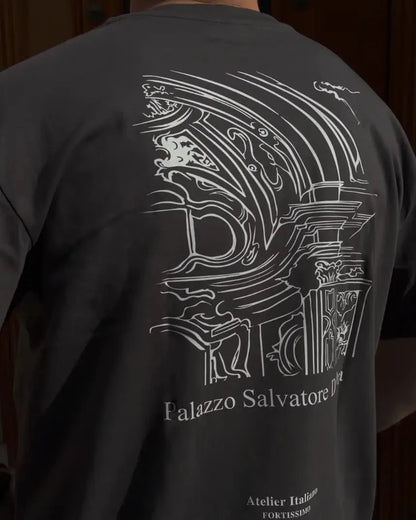 Person wearing a black t-shirt with white architectural design and text on the back.