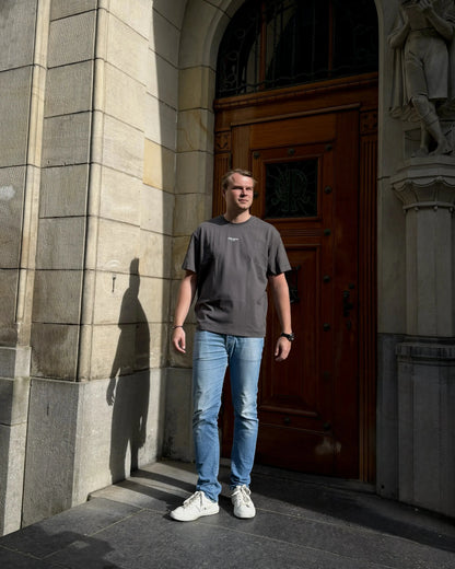 Man standing in front of a large wooden door with stone architecture